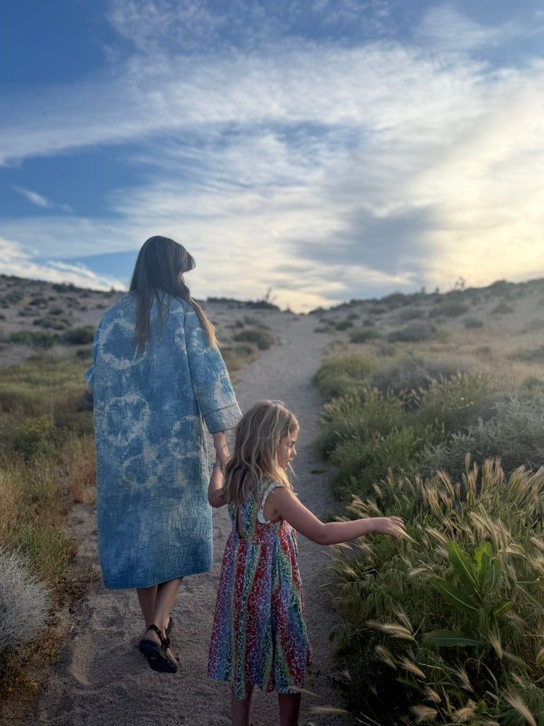 Colleen and Willow walking hand in hand along a sunlit path among grasses